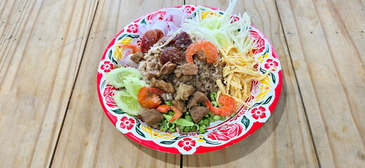 Shrimp Paste Fried Rice served with various side dishes such as sweet pork, fried dried shrimp, sliced shallots, sour mango. Rice mixed with Shrimp Paste put in brightly patterned plate. local food.
