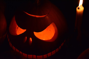 A close-up of a carved Jack-o'-lantern glowing in the dark. The image conveys a spooky and festive Halloween atmosphere.