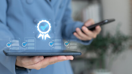 Businesswoman holding tablet showing certified approval and checklist icons on virtual screen, document verification and quality assurance concept