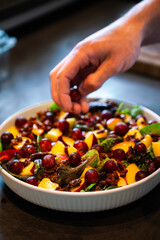 Han of a person preparing a healthy summer salad, with homegrown fruit and vegetables. Popular in...