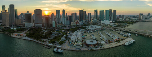 Naklejka premium High illuminated skyscrapers of Brickell, city's financial center. Skyviews Miami Observation Wheel at Bayside Marketplace with reflections in Biscayne Bay water and US urban landscape at sunset