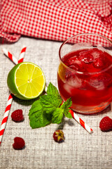 Berry cocktail with lime and mint, served with a straw. Vibrant refreshment in rustic style. Cozy and refreshing table scene.
