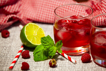 Chilled berry drinks with lime and mint on rustic fabric. Vibrant summer mood in warm light.