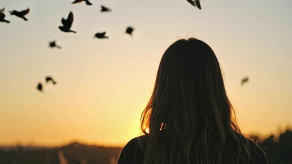 Woman standing at sunset with flying doves, serene mental health concept