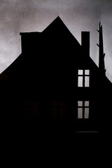 Silhouette of a low residential building with windows and a tree