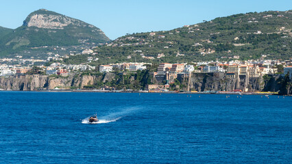 Sorrento Coast Boat Tour. A boat sailing the blue waters of the Gulf of Naples, with Sorrento and Vesuvius in view.