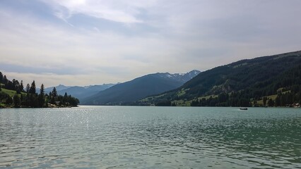 Fototapeta premium Panoramic scene featuring a lake bordered by undulating hills and cloudy weather