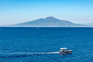 Sorrento Coast Boat Tour. A boat sailing the blue waters of the Gulf of Naples, with Sorrento and Vesuvius in view.