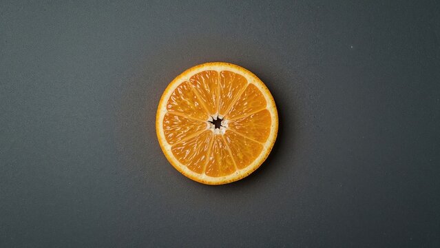 Tasty Orange Segment Against a Neutral Gray Backdrop with Light and Shadow Effects