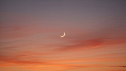 Fototapeta premium Summer and autumn sky background with a crescent moon illuminated by sunset colors