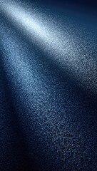 A dramatic spotlight illuminates a textured dark surface