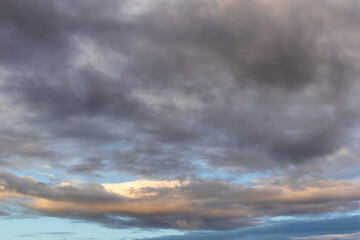 Obraz premium Dramatic evening clouds with patches of blue sky and warm light