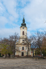 The Monastery of the Holy Trinity in Kikinda features a tall bell tower and soft baroque architecture. Surrounded by trees, it embodies serene Serbian religious heritage.