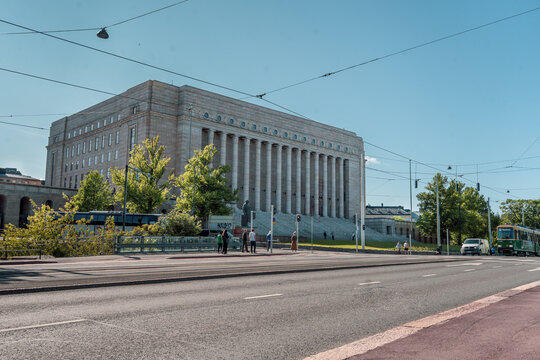 The Finnish Parliament Building in Helsinki captured on a bright, sunny day, highlighting its architectural details and vibrant surroundings.