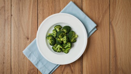 A dish of broccoli resting on a blue napkin atop a wooden background