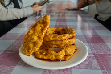 Golden, crisp, and drizzled with sweet chancaca syrup, these Arequipa-style picarones are a delicious blend of pumpkin and sweet potato dough, fried to perfection and served as a Peruvian treat.