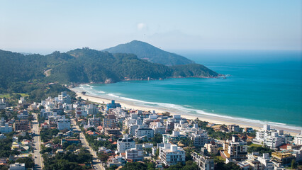 Naklejka premium Aerial view of Mariscal Beach with turquoise waters and coastal cityscape, Santa Catarina, Brazil.