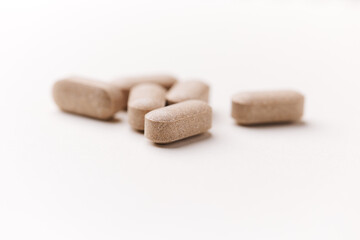 Lion’s mane mushrooms tablets that have beneficial effects on the body, especially the brain, heart, and intestines. Bright paper background. Soft focus. Close up. Copy space.	