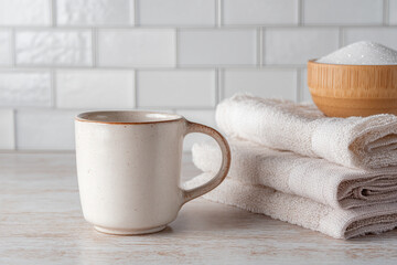A ceramic mug and handmade sugar bowl displayed next to folded linen napkins on a retro kitchen countertop.