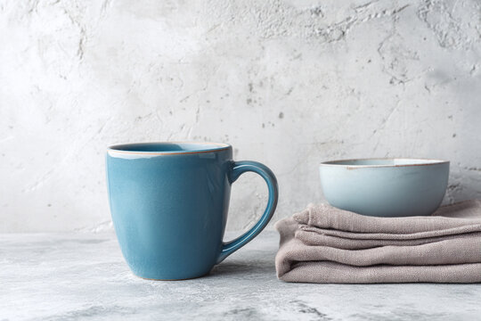 A ceramic mug and handmade sugar bowl displayed next to folded linen napkins on a retro kitchen countertop.