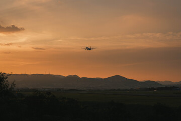 伊丹スカイパーク、夕暮れ時の茜色の空へ飛び立つ飛行機、大阪、日本