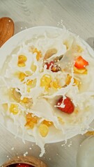 Granola Pouring and Splashing into the White Bowl with Milk. Served on Kitchen Table. Concept of Flying Food. Overhead View.