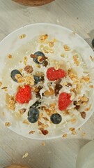Granola Pouring and Splashing into the White Bowl with Milk. Served on Kitchen Table. Concept of Flying Food. Overhead View.