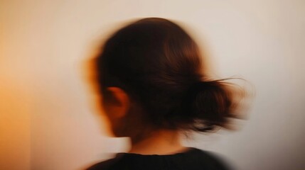 A blurry image of a woman with a bun on her head. The woman's face is barely visible, but her hair is the main focus of the image. Scene is somewhat mysterious and somewhat unsettling