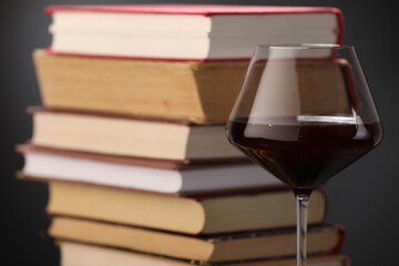 Red wine in glass and stack of books on dark background, closeup