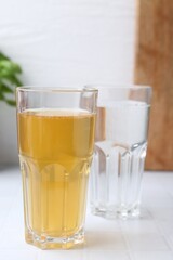 Glasses with clean and dirty water on white tiled table, closeup
