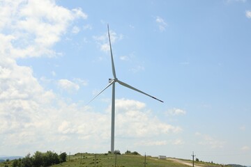 Fototapeta premium Modern wind turbine in field on sunny day