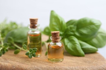 Bottles of essential oil and herbs on table, closeup