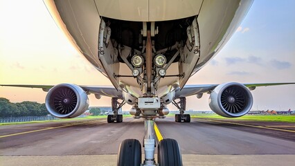 Detailed front shot of airplane nose gear and engines aligned symmetrically on airport taxiway © Sarmiko.id