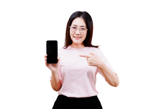 Asian young beautiful woman in glasses points to a smartphone, showcasing it with a smile while wearing a light pink shirt.