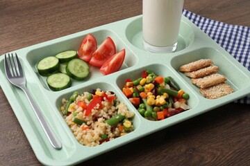 Plastic tray with tasty food, milk and fork on wooden table, closeup. School lunch