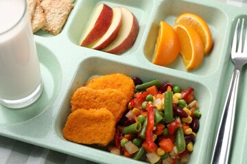 Plastic tray with tasty food, milk and fork on table, above view. School lunch