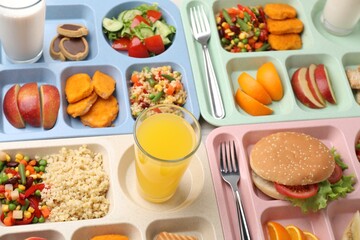 Plastic trays with tasty food, milk and orange juice on table, above view. School lunch