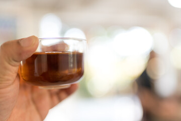 Warm tea in glass cup on hand against blur background