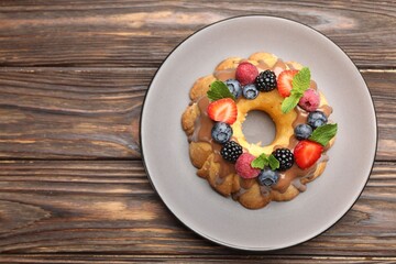 Tasty Bundt cake with berries, chocolate and mint on wooden table, top view. Space for text