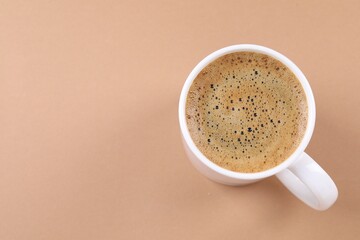 Aromatic coffee in cup on beige background, above view. Space for text