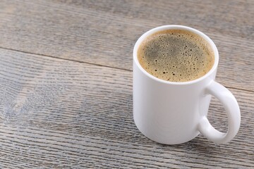Aromatic coffee in cup on wooden table, closeup. Space for text