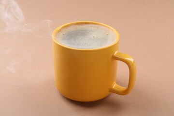 Aromatic coffee in cup on beige background, closeup