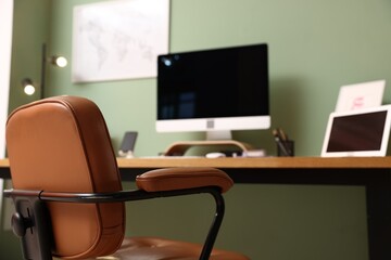 Stylish workplace with modern computer on wooden desk indoors, focus on office chair
