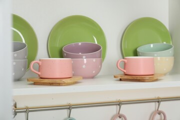 Different dishware and cups on shelf in cabinet indoors, closeup
