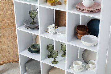 Shelving unit with different dishware, glasses and cups indoors