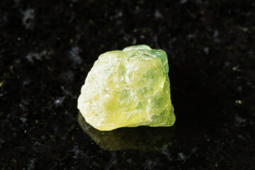 raw yellow green sapphire corundum stone on black