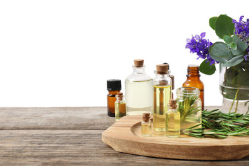 Bottles of essential oils and different plants on wooden table against white background