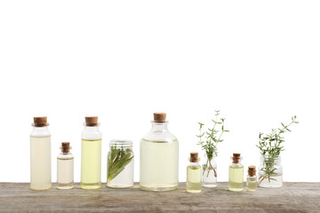 Bottles of essential oils, rosemary and thyme on wooden table against white background
