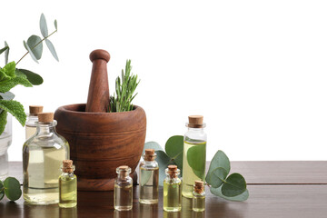 Bottles of essential oils and different plants on wooden table against white background