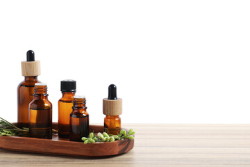 Bottles of essential oils and different herbs on wooden table against white background